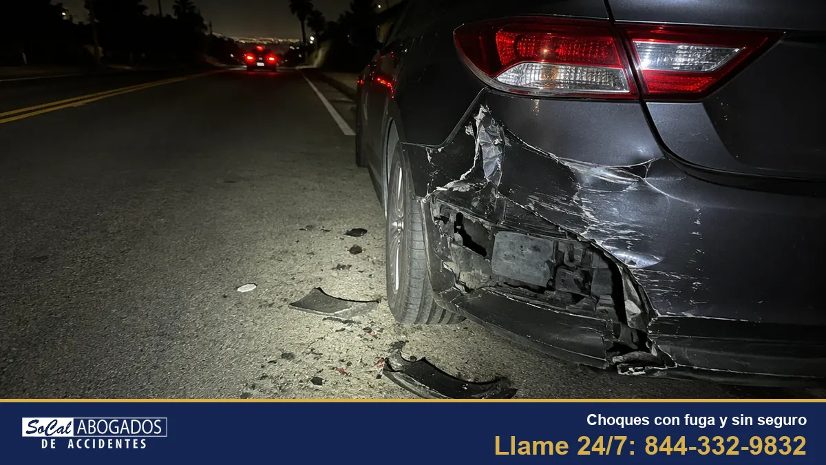 Carro con la defensa trasera destrozada de noche mientras el otro carro se aleja